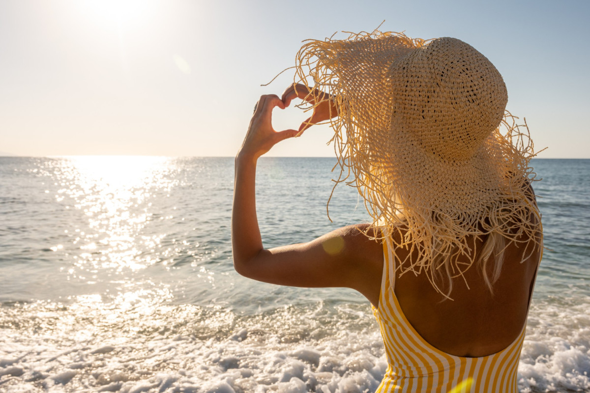 Une femme sur la plage avec chapeau de paille