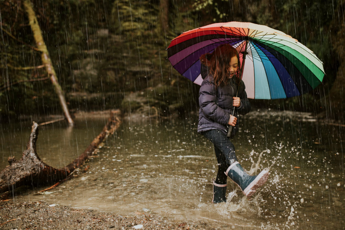 Une petite fille joue sous la pluie