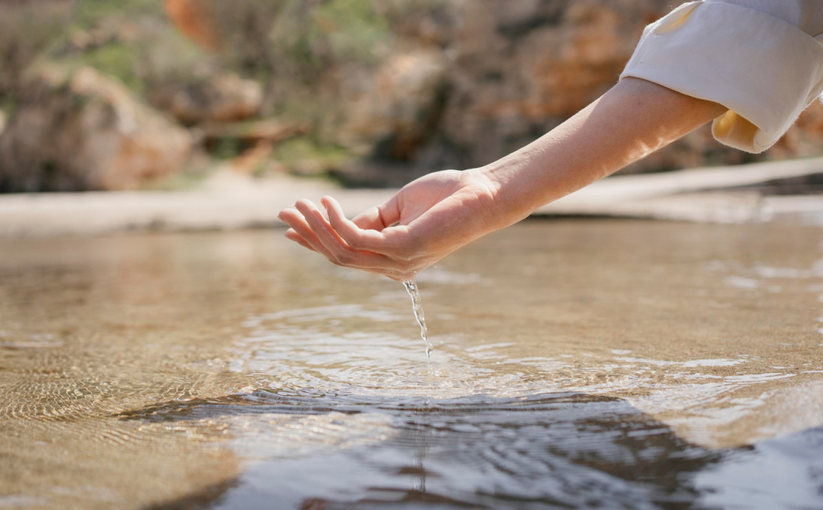 Une femme plonge sa main dans l'eau d'une rivière