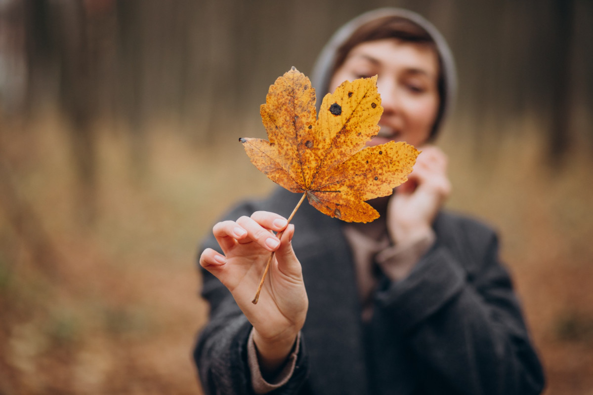 Une femme tient une feuille morte