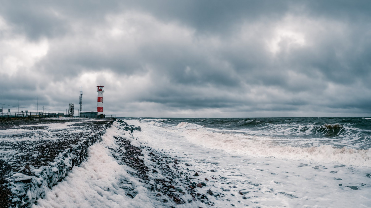 Mer agitée devant une plage et un phare