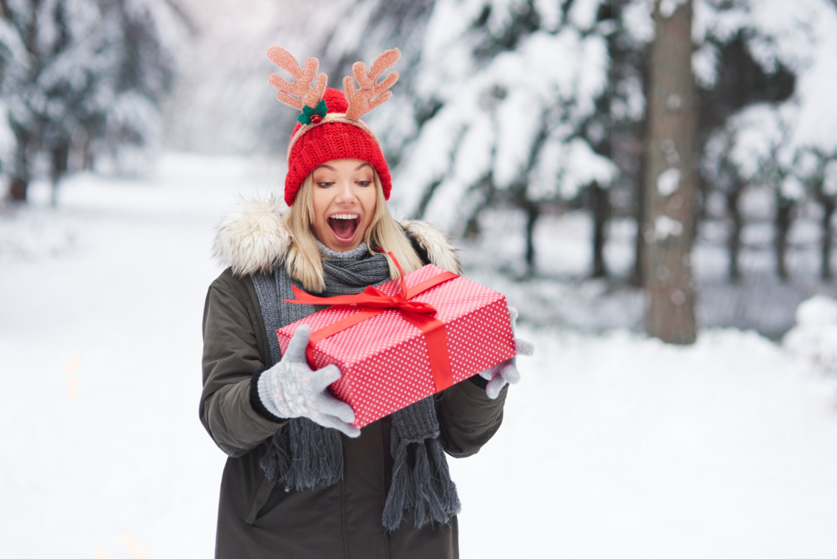 Une femme dehors tient un cadeau de Noël