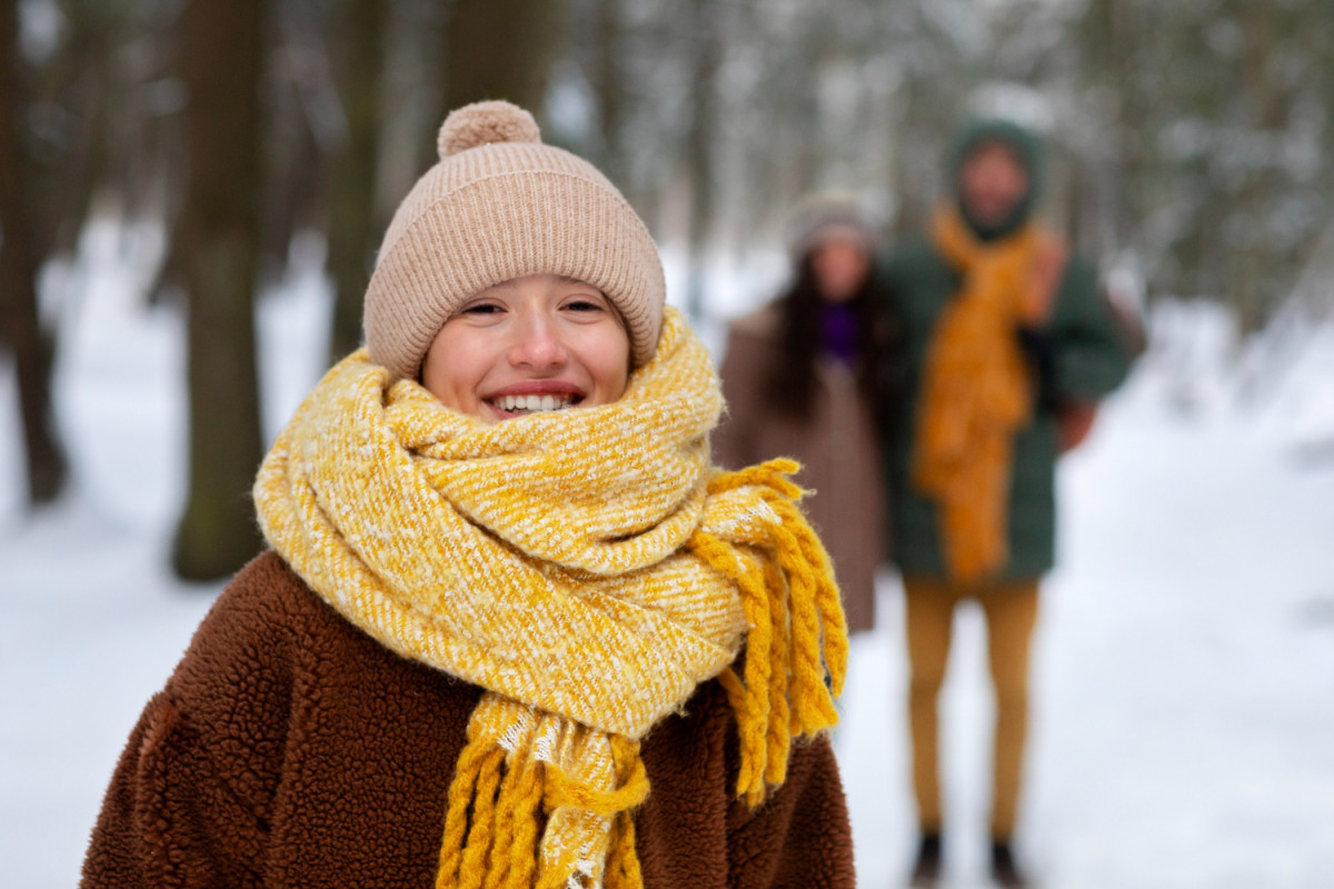 Une femme dehors avec une grosse écharpe jaune