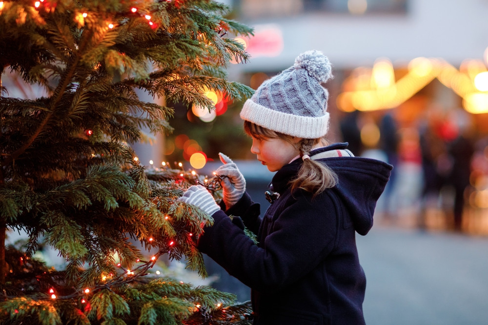 Une petite fille à côté d'un sapin de Noël