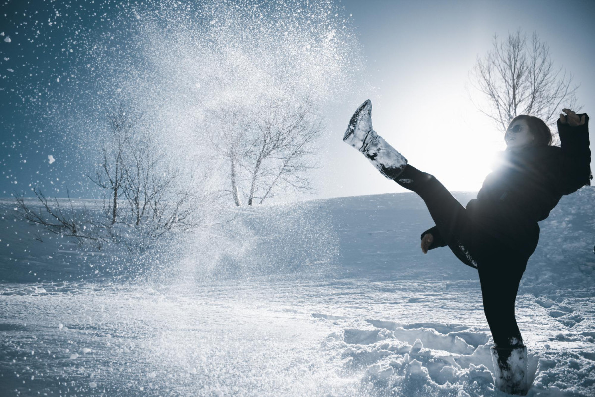 Une femme joue avec de la neige en montagne