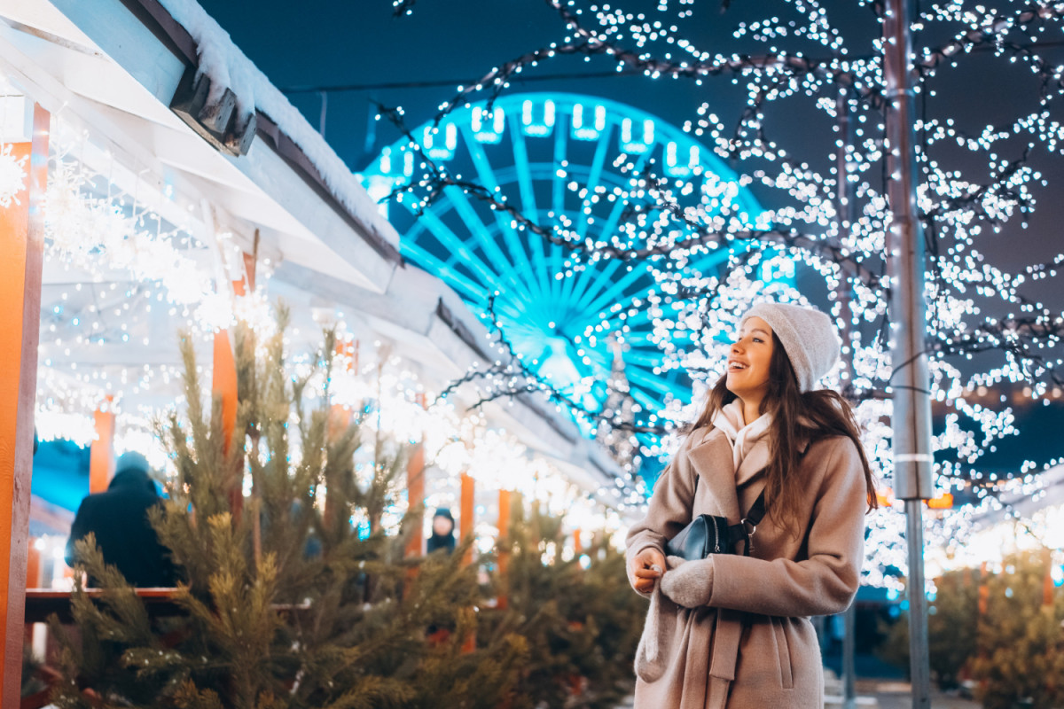 Une femme devant une grande roue illuminée