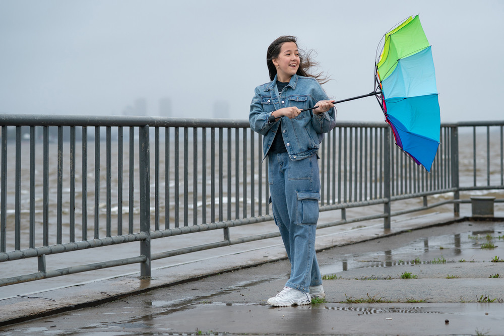 Une femme tient un parapluie retourné par le vent