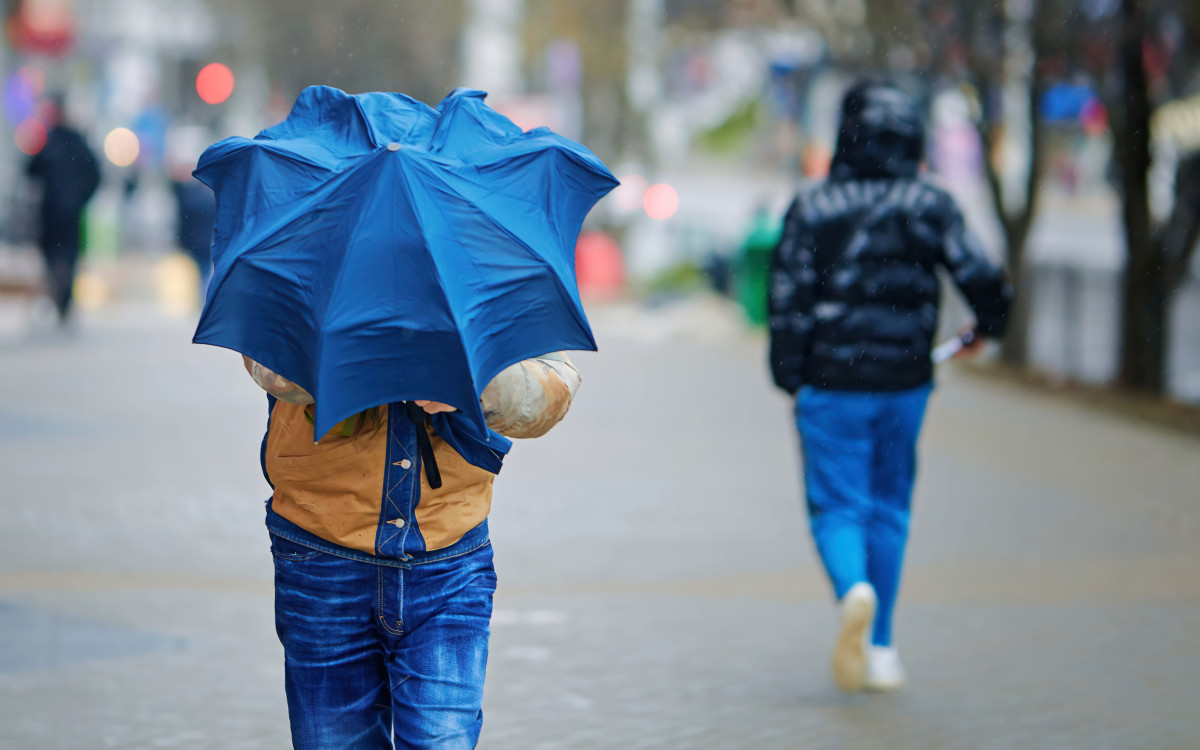 Un homme lutte contre le vent avec son parapluie