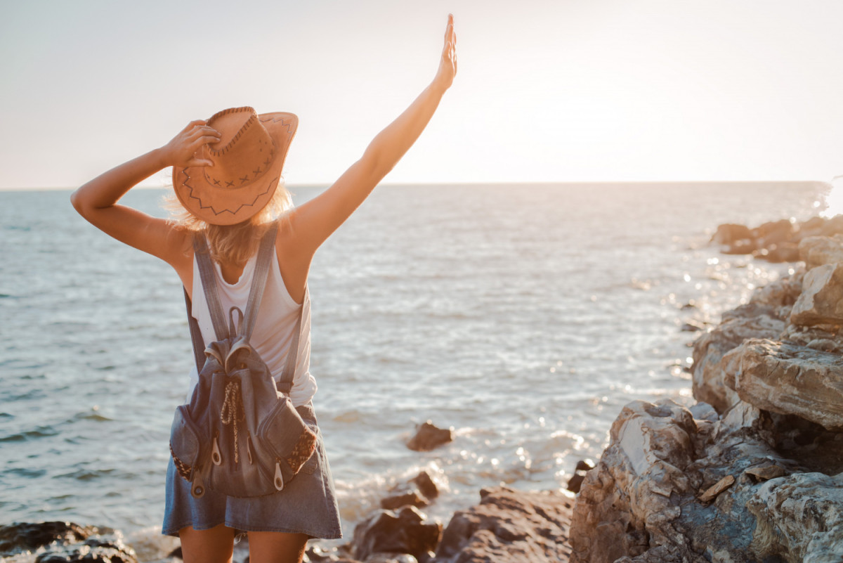 Une femme debout face à la mer et le soleil