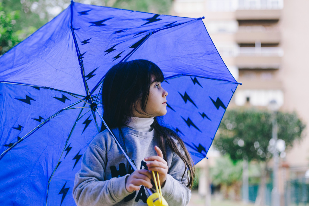 Une enfant tient un parapluie bleu