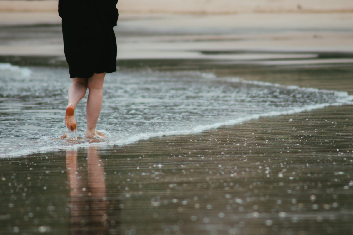 Une femme marche sous la pluie sur la plage