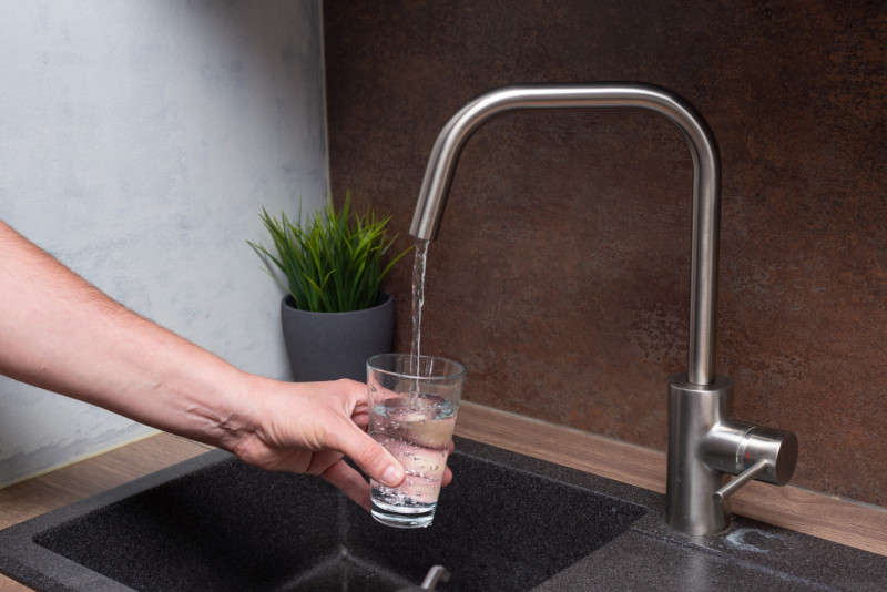 Quelqu'un remplit un verre d'eau au robinet1830