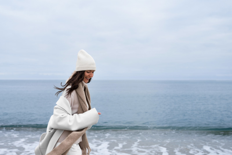 Une femme avec un bonnet court sur la plage