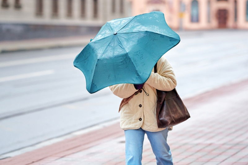 Une femme avec un parapluie lutte contre le vent