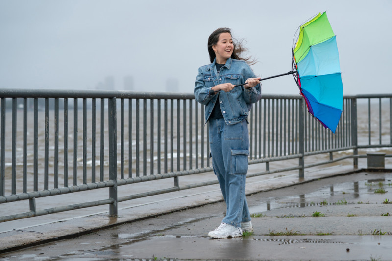 Une femme tient un parapluie retourné par le vent2297