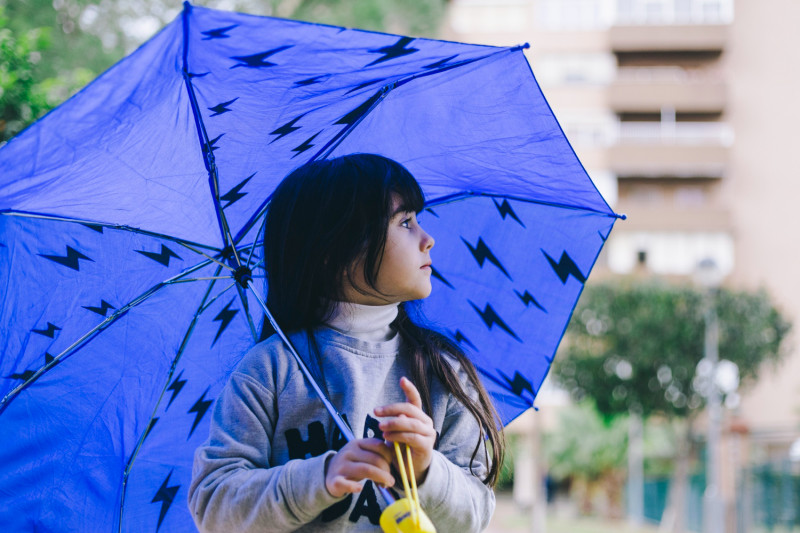 Une enfant tient un parapluie bleu