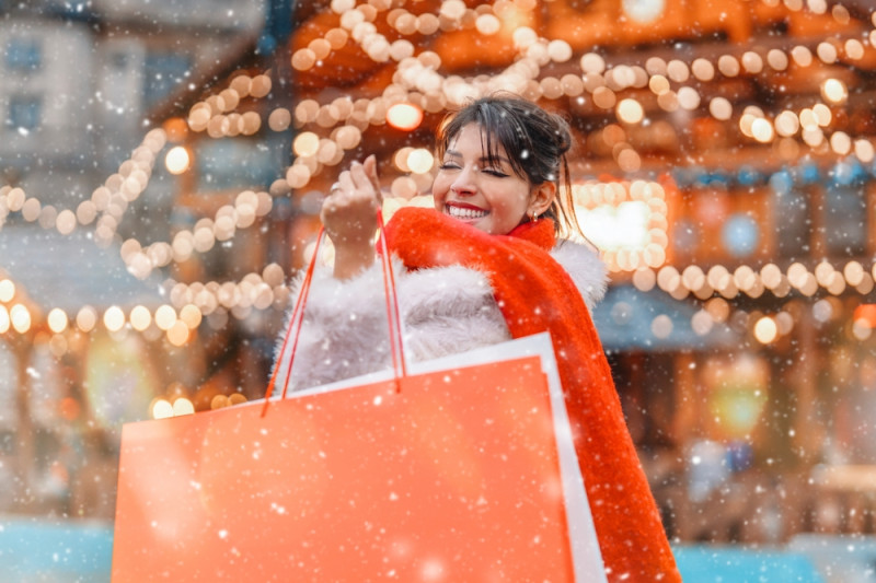 Une femme se promenant avec un sac à Noël sous la neige