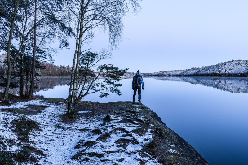 Homme debout près d'un lac
