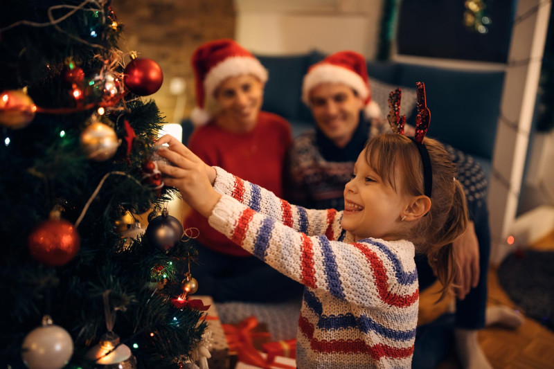 Une petite fille décore un sapin de noel