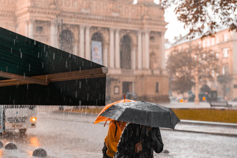 Des personnes marchent sous la pluie avec un parapluie