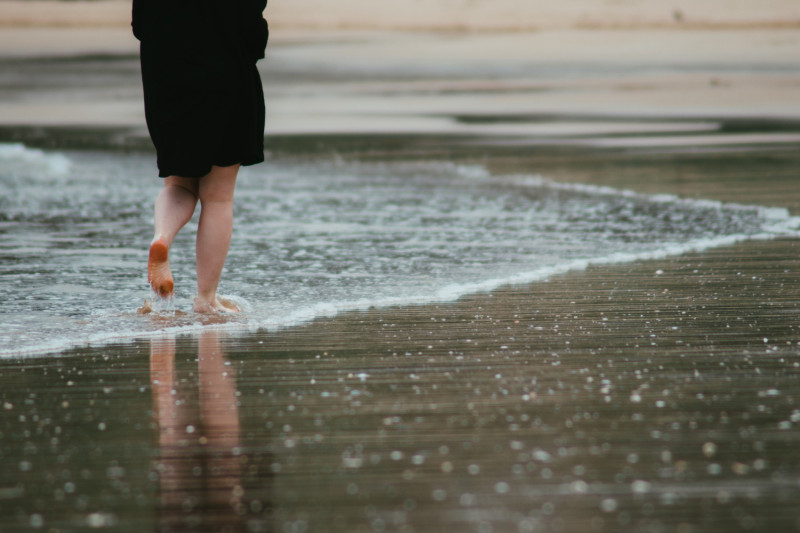 Une femme marche sous la pluie sur la plage