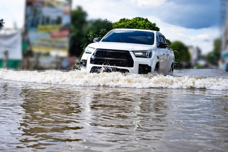 Une voiture roule dans une rue inondée