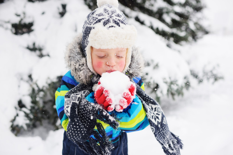 Un enfant tient une grosse boule de neige