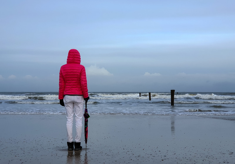 Une femme face à la plage en hiver