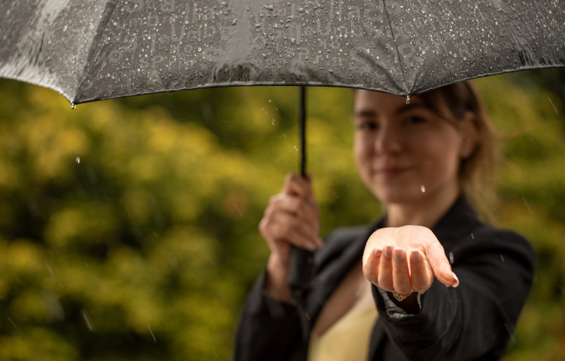 Une femme tend sa main sous un parapluie