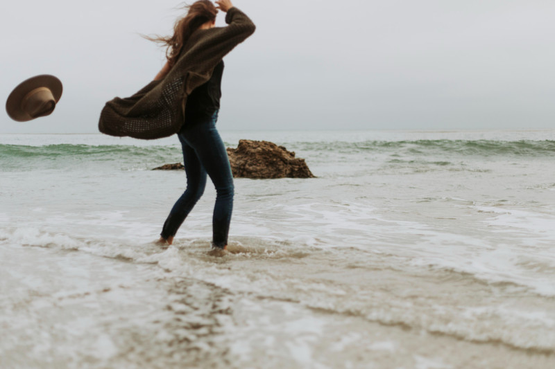 Une femme sur la plage face au vent
