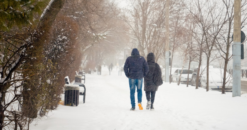 Deux personnes marchent dans une rue enneigée