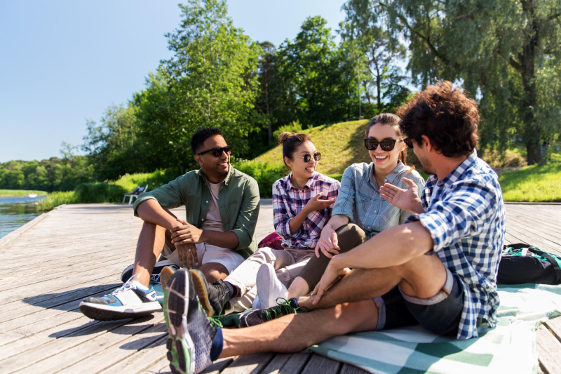 Un groupe d'amis discute sur la berge d'un fleuve au soleil