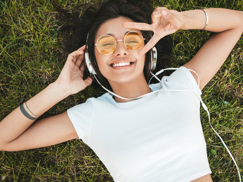 Une jeune femme est allongée dans l'herbe avec son casque audio