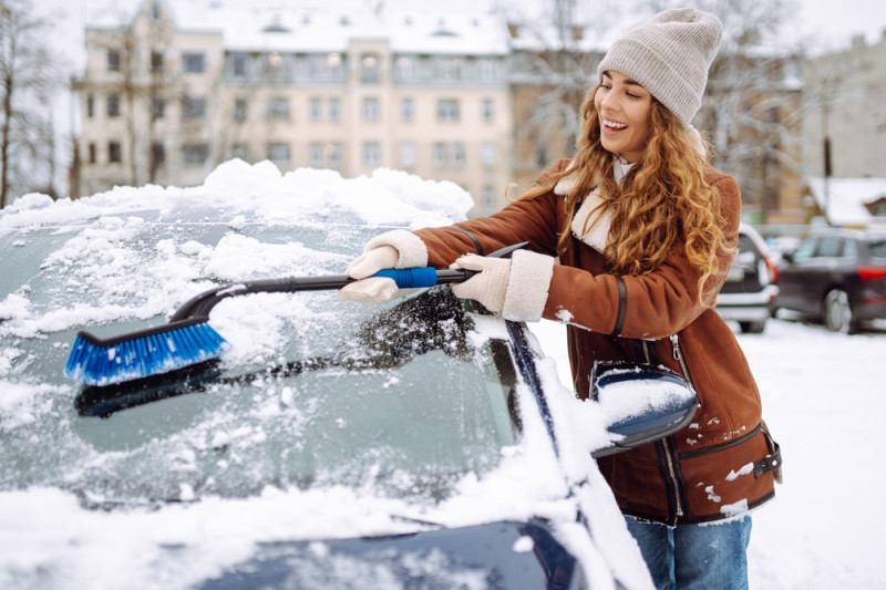 Une femme enlève la neige de son parebrise