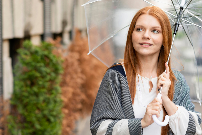 Une femme rousse tient un parapluie