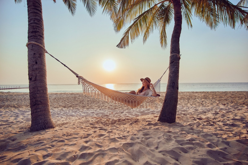 Une femme sur un hamac entre deux palmiers