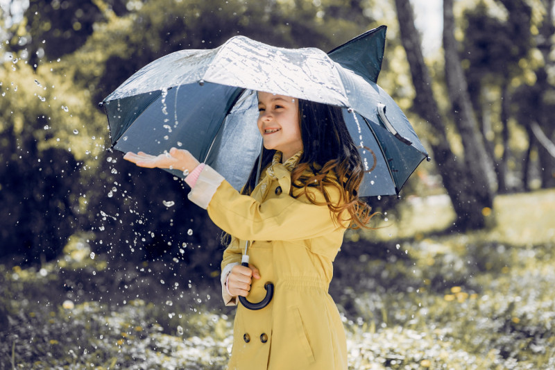 Petite fille joue avec la pluie