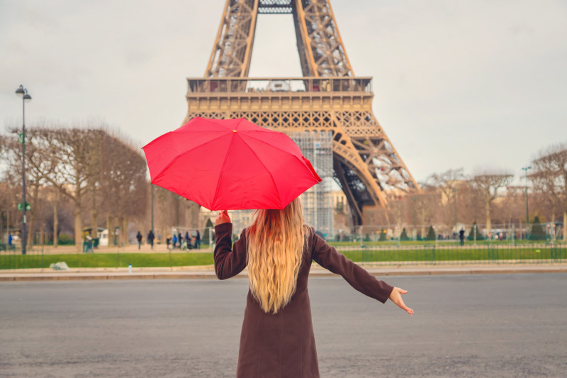 Une femme face à la tour eiffel avec un parapluie