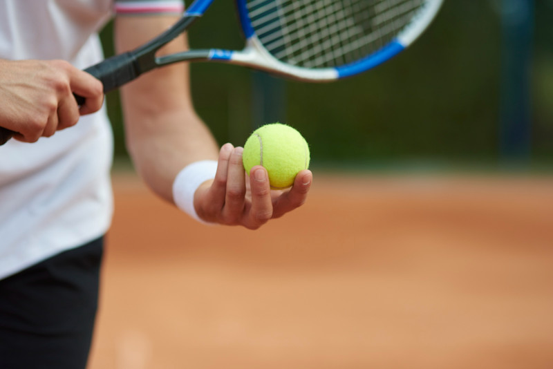 Un homme tient une balle de tennis