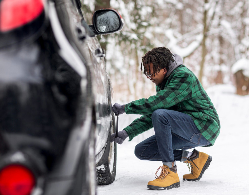 Un homme change le pneu de sa voiture