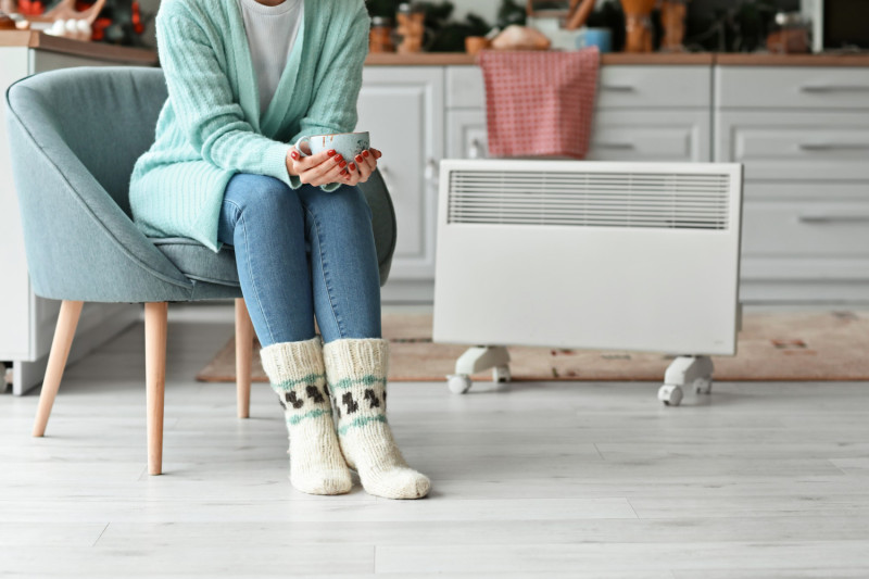 Une femme assise près d'un chauffage