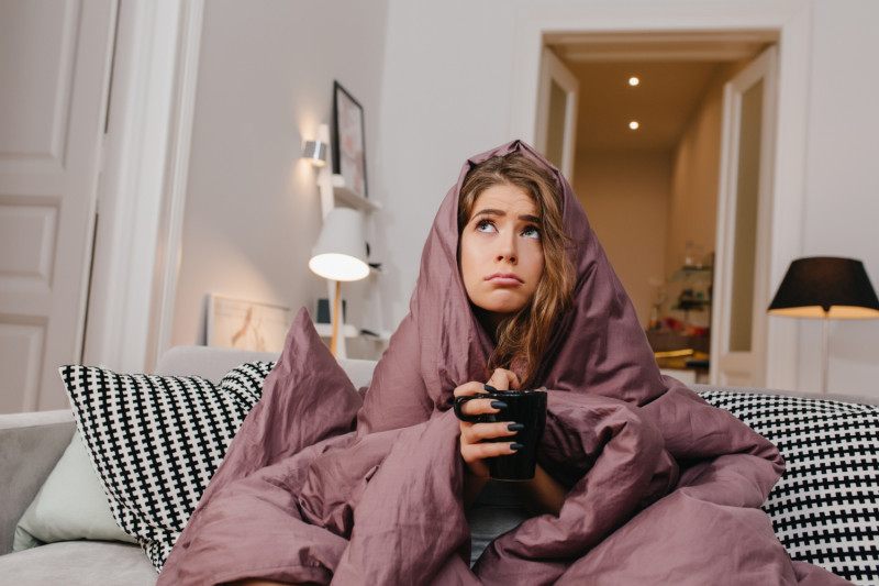 une femme enroulée dans une couverture sur son canapé