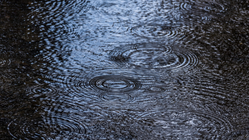 De la pluie tombe dans une flaque d'eau