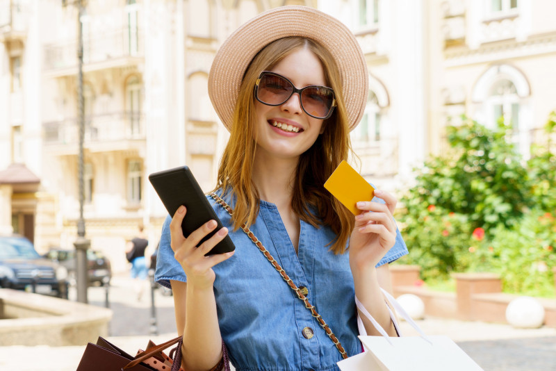 Une femme en voyage tient sa carte bancaire