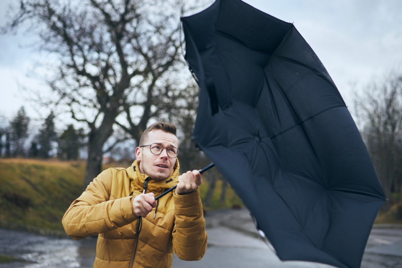 Un homme avec un parapluie qui s'envole à cause du vent