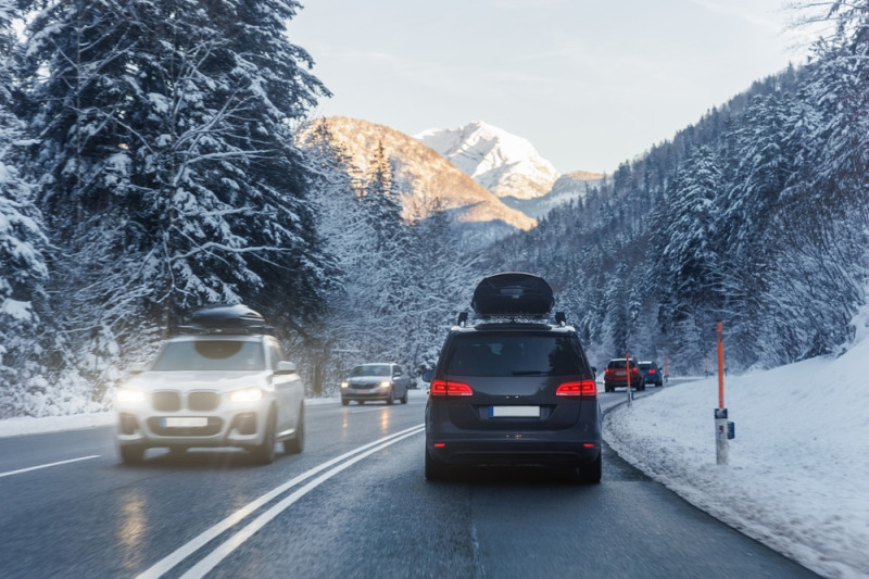 Voiture avec coffre de toit sur une route enneigée