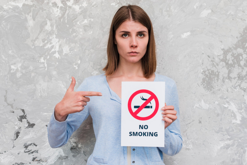 Femme tenant un panneau interdit de fumer