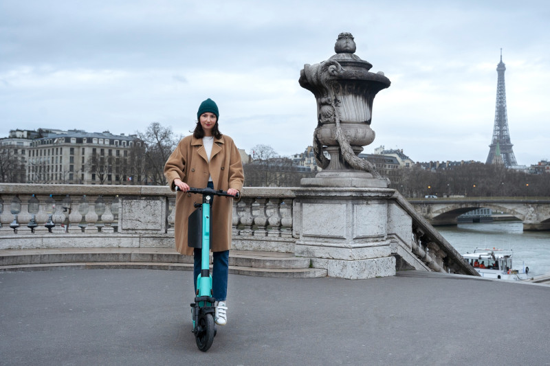Femme sur une trottinette avec la tour effeil