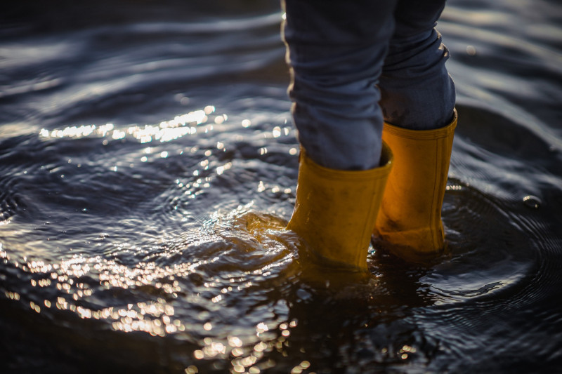 Zoom sur les bottes d'un enfant qui marche dans l'eau