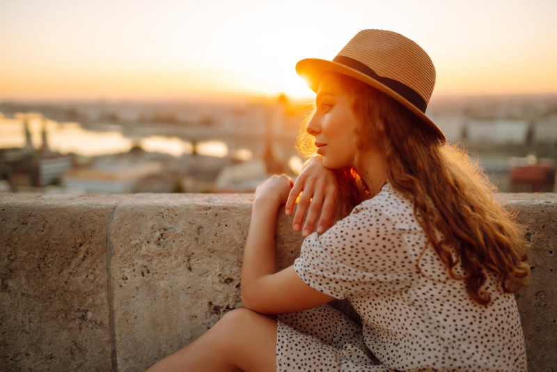 Une femme assise au soleil avec un chapeau de paille